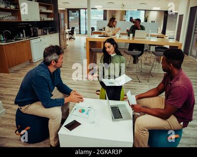 Verschiedene Partnergruppen treffen sich, um die Papierarbeit zu besprechen, bevor sie sich mit dem Vorgesetzten und den Kunden treffen Stockfoto