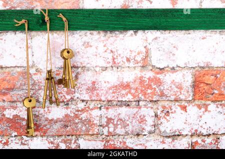 Alte Messing Metall Türschlüssel hängen von der Schnur an einem rustikalen Backstein Wand Textur Hintergrund Stockfoto