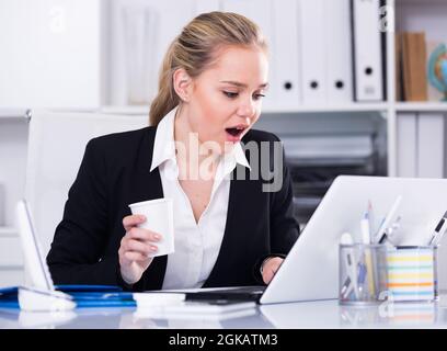 Eine Geschäftsfrau, die den Monitor überrascht ansieht Stockfoto