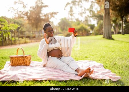 Schwangere afroamerikanische Frau macht Videoanruf Stockfoto