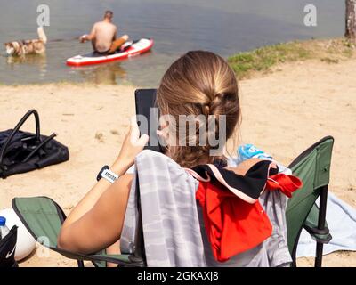 Nass Husky Hund und Spray von Wasser. Ein schöner Husky schwimmend im See. Hund steht auf dem SUP-Brett. Sommerzeit- und Urlaubskonzept. Platz kopieren. Stockfoto