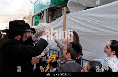 Ein ultra-orthodoxer jüdischer Mann schwingt ein Huhn über den Kopf eines Mitglieds seiner Familie, während er die Kapparot-Zeremonie vor Yom Kippur im Viertel Mea Shearim, einer ultra-orthodoxen Enklave in Jerusalem, Israel, durchführt. Kapparot ist ein übliches Sühneritual, das von einigen religiösen Juden praktiziert wird, bei dem die Sünden einer Person symbolisch auf ein Geflügel übertragen und dann am Nachmittag vor Yom Kippur geopfert werden. Der Versöhnungstag, der als einer der heiligsten und feierlichsten Tage des jüdischen Kalenders gilt. Stockfoto