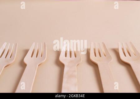 Holzgabeln liegen in einer Reihe auf einem cremefarbenen Hintergrund. Rhythmus. Umweltfreundliches Konzept. Horizontale Ausrichtung. Speicherplatz kopieren. Stockfoto
