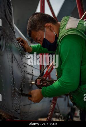 PAZIFISCHER OZEAN (1. März 2021) U.S. Navy Aviation Structural Mechanic 2nd Class James Han, aus Tian Jin, China, zugewiesen an die „Magier“ des Hubschrauber-Seestreikgeschwaders (HSM) 35, Zieht einen Bolzen auf dem Schwanz eines MH-60R Sea Hawk auf dem Flugdeck des Arleigh Burke-Klasse Lenkraketen-Zerstörers USS John Finn (DDG 113) am 1. März 2021. John Finn, Teil der Theodore Roosevelt Carrier Strike Group, ist im geplanten Einsatzgebiet der 7. US-Flotte unterwegs. Als größte vorwärtseingesetzte Flotte der US-Marine arbeitet die 7. Flotte routinemäßig mit 35 maritimen Schiffen zusammen Stockfoto