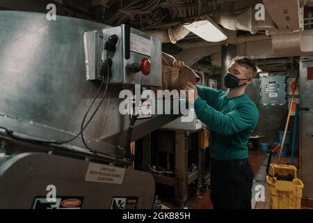 PAZIFISCHER OZEAN (2. März 2021) – Tyler McDonald, Auszubildender der U.S. Navy Aviation Structural Mechanic Airman aus Massena, N.Y., verdichtet Müll an Bord des Flugzeugträgers USS Theodore Roosevelt (CVN 71), 2. März 2021. Die Theodore Roosevelt Carrier Strike Group ist im geplanten Einsatz im 7. Flottenbereich der USA. Als größte vorwärtseingesetzte Flotte der US-Marine operiert und interagiert die 7. Flotte routinemäßig mit 35 maritimen Nationen und führt Missionen durch, um eine freie und offene Indo-Pazifik-Region zu erhalten und zu schützen. Stockfoto