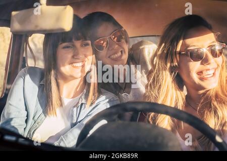 Drei fröhliche Freundinnen, die im Auto unterwegs sind. Mädchen Freunde Spaß haben, während genießen Autofahrt an einem hellen Sommerurlaub. Weibliche Freunde Stockfoto