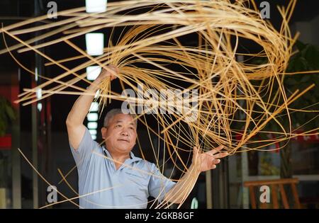 (210914) -- XINYU, 14. September 2021 (Xinhua) -- Li Nian'gen stellt Bambuswebprodukte in der Gemeinde Dongcun, Bezirk Fenyi, Stadt Xinyu in der ostchinesischen Provinz Jiangxi, her, 2. September 2021. Li Nian'gen, 62, ist die fünfte Generation der Bambuswebtechniken in der Gemeinde Dongcun. Li erwarb Bambuswebtechniken von seinem Onkel, als er gerade einmal neun Jahre alt war, und begann mit 15 Jahren, seinen Lebensunterhalt allein zu verdienen. Mehr als 20 seiner Lehrlinge entschieden sich Anfang der 1990er Jahre, in anderen Lebensbereichen außerhalb seiner Heimat eine Beschäftigung für besseres Einkommen zu suchen, aber Li beschloss, zu bleiben und sich an seine p zu halten Stockfoto