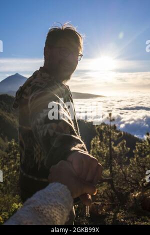 Ein paar Abenteuerreisende. Silhouette des Mannes folgen Frau Hände halten Wandern auf Berglandschaft. Pärchen genießen das Wandern auf dem Gipfel des Berges Stockfoto