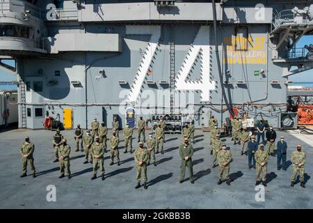 Matrosen, die dem Flugzeugträger USS John C. Stennis (CVN 74) zugewiesen wurden, die vor kurzem verdientermaßen zum Kleinoffizier der dritten Klasse vorgerückt wurden, posieren für ein Foto auf dem Flugdeck mit der Kommandotriade. John C. Stennis arbeitet mit Newport News Shipbuilding zusammen, um die Überholung des Tankkomplexes planmäßig mit einer geschulten, widerstandsfähigen und geschlossenen Crew abzuschließen. Stockfoto