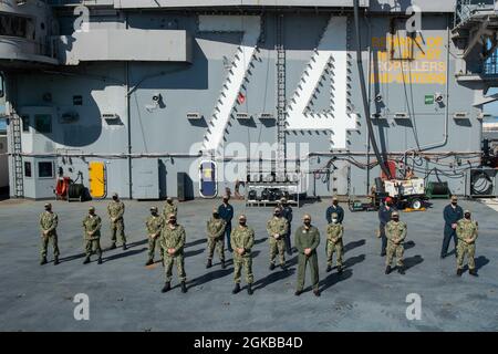 Matrosen, die dem Flugzeugträger USS John C. Stennis (CVN 74) zugewiesen wurden, die vor kurzem verdientermaßen zum Kleinoffizier zweiter Klasse vorgerückt wurden, posieren für ein Foto auf dem Flugdeck mit der Kommandotriade. John C. Stennis arbeitet mit Newport News Shipbuilding zusammen, um die Überholung des Tankkomplexes planmäßig mit einer geschulten, widerstandsfähigen und geschlossenen Crew abzuschließen. Stockfoto