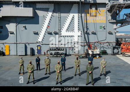 Matrosen, die dem Flugzeugträger USS John C. Stennis (CVN 74) zugewiesen wurden, die vor kurzem verdientermaßen zum Kleinoffizier erster Klasse vorgerückt wurden, posieren für ein Foto auf dem Flugdeck mit der Kommandotriade. John C. Stennis arbeitet mit Newport News Shipbuilding zusammen, um die Überholung des Tankkomplexes planmäßig mit einer geschulten, widerstandsfähigen und geschlossenen Crew abzuschließen. Stockfoto