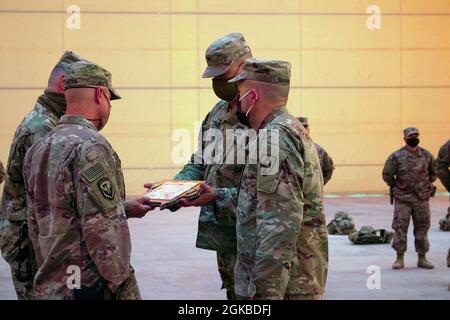 Col. Mark Coble und Sgt. Maj. John Shannon, 734. Regionale Unterstützungsgruppe, überreichen ein Geschenk an das scheidende Kommandoteam, Col. Robert Martinez und Command Sgt. Maj. John Hicks, während einer Zeremonie zur Übertragung der Autorität auf dem Luftwaffenstützpunkt Al Asad, Irak, am 3. März 2021. Coble, Shannon und das 734. RSG-Team übernahmen die Funktionen des Base Operation Support Integrators und Base Camp Services zur Unterstützung der operationsinhärenten Lösung. Stockfoto