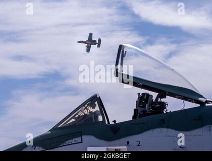 Ein A-10 Thunderbolt II ruht auf der Fluglinie, als US Air Force Capt. Haden 'Gator' Fullam, A-10 Warthog Demonstration Teamkommandant und Pilot fliegt auf der Heritage Flight Training Conference 2021 auf der Davis-Monthan Air Force Base, Arizona, am 4. März 2020 über dem Flugzeug. Die Heritage Flight Training Conference ist eine jährliche Veranstaltung zur Zertifizierung neuer Air Combat Command-Einschiff-Demonstrationsteams sowie zum Training von Formationsflügen an historischen Militärflugzeugen. Stockfoto