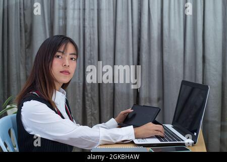Junge malaysische Frau, die in ihrem Büro an einem Laptop arbeitet Stockfoto