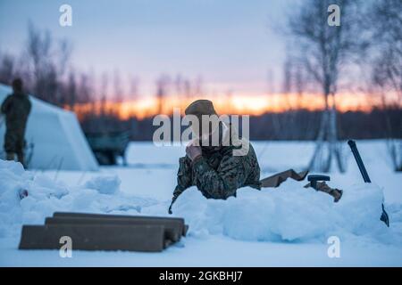 U.S. Marine Corps CPL. Cody Dixon, ein Kraftfahrzeugbetreiber, passt seine Gesichtsbedeckung an, während er während eines Überlebenstrainings bei kaltem Wetter auf Fort Drum, New York, am 4. März 2021, einen Schneeschutz baute. Marines of Combat Logistics Bataillon 8 erleichtern Marines in der 2. Marine Logistics Group das Überleben bei kaltem Wetter und die Kurse für den Motortransport. Stockfoto