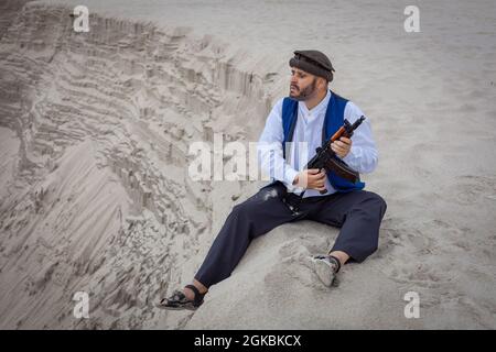 Ein Soldat der Taliban überwacht eine Straße in Afghanistan. Ein Soldat steht mit einer Waffe auf der Wache, um zu töten. Stockfoto