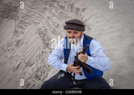 Ein Soldat der Taliban überwacht eine Straße in Afghanistan. Ein Soldat steht mit einer Waffe auf der Wache, um zu töten. Stockfoto