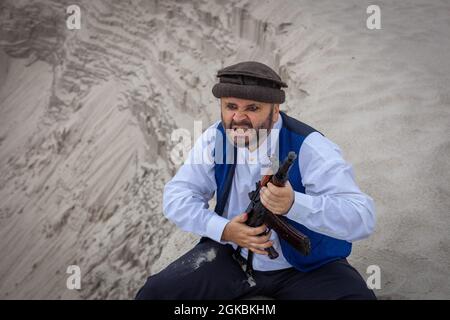 Ein Soldat der Taliban überwacht eine Straße in Afghanistan. Ein Soldat steht mit einer Waffe auf der Wache, um zu töten. Stockfoto