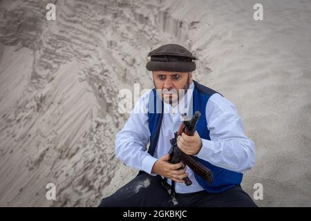 Ein Soldat der Taliban überwacht eine Straße in Afghanistan. Ein Soldat steht mit einer Waffe auf der Wache, um zu töten. Stockfoto