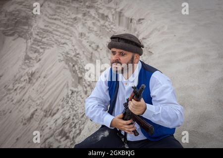 Ein Soldat der Taliban überwacht eine Straße in Afghanistan. Ein Soldat steht mit einer Waffe auf der Wache, um zu töten. Stockfoto