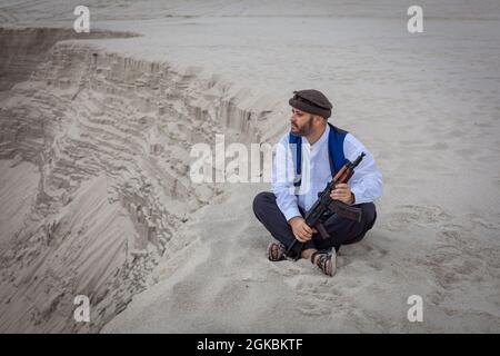 Ein Soldat der Taliban überwacht eine Straße in Afghanistan. Ein Soldat steht mit einer Waffe auf der Wache, um zu töten. Stockfoto