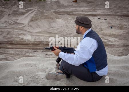 Ein Soldat der Taliban überwacht eine Straße in Afghanistan. Ein Soldat steht mit einer Waffe auf der Wache, um zu töten. Stockfoto