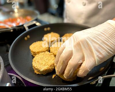 Sgt. Sarah Perry, 1. Klasse, als Hilfskraft von LT. General Jody J. Daniels, Chef der Army Reserve und kommandierender General, U.S. Army Reserve Command, Und andere kulinarische Spezialisten der Armee bereiteten während eines Besuchs von John E. Whitley, amtierender Sekretär der US-Armee, 5. März 2021, eine Mahlzeit für hochrangige Führungskräfte vor. Stockfoto