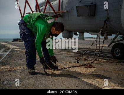 PACIFIC OCEAN (5. März 2021) U.S. Navy Aviation Structural Mechanic 2nd Class James Han, aus Tian Jin, China, wurde den „Magiern“ des Helicopter Maritime Strike Squadron (HSM) 35 zugewiesen und löst auf dem Flugdeck des Arleigh Burke-Klasse-Lenkflugzeugzerstörers USS John Finn (DDG 113) eine Kette von einem Vorhängeauge. 5. März 2021. John Finn, Teil der Theodore Roosevelt Carrier Strike Group, ist im geplanten Einsatzgebiet der 7. US-Flotte unterwegs. Als größte vorwärtseingesetzte Flotte der US-Marine arbeitet die 7. Flotte routinemäßig und interagiert während der Führung mit 35 maritimen Nationen Stockfoto