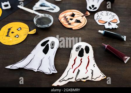 Gruppe von handgefertigten Papier halloween-Symbole und Ölfarben auf schwarzem Holztisch Stockfoto