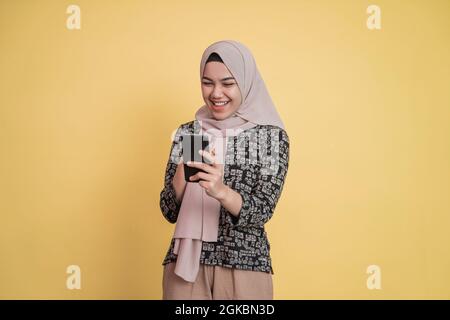 asian verschleierte Frau Blick auf den Bildschirm, während mit einem Smartphone mit glücklicher Ausdruck Stockfoto