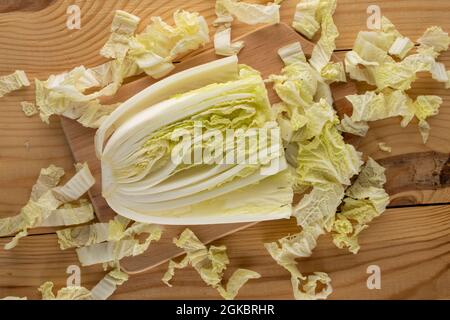 Eine Hälfte und zerkleinert frischen chinesischen Kohl auf einem Holztisch, Nahaufnahme, Draufsicht. Stockfoto