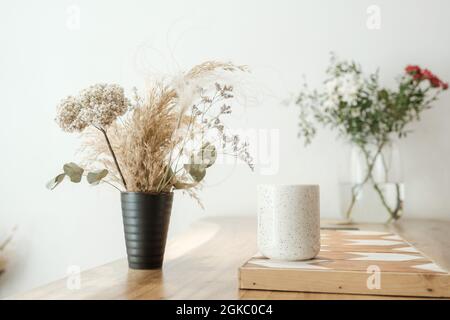 Getrocknetes Gras in Vasen steht auf einem weißen Tisch. Stockfoto