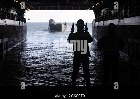 210308-N-PC065-1054 ATLANTISCHER OZEAN (8. März 2021) Boatswains Mate 2nd Class Dwayne Walker aus Manchester, Jamaika, leitet Landing Craft Utility (LCU 1662) in das Brunnendeck des Amphibientransportschiffes USS Arlington (LPD 24) der San Antonio-Klasse, 8. März 2021. Arlington ist im Atlantischen Ozean unterwegs. Stockfoto