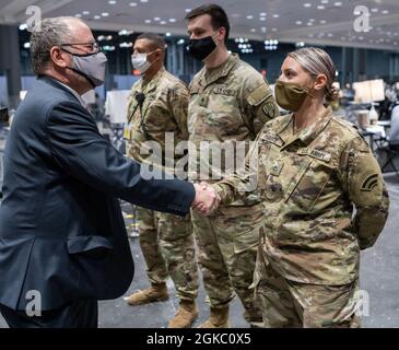 Steve A. Castleton, ein ziviler Berater des Armeeministers, präsentiert eine Challenge-Münze an die New Yorker Nationalgarde PFC Dinamarie Parente, einen LKW-Fahrer, der der E Company zugewiesen wurde. 3. Bataillon, 142. Aviation bei einem Besuch des Jacob Javits Convention Center, das am 8. März 2021 in eine Massenimpfstelle umgewandelt wurde. Castleton besuchte während der Nachtschicht die Sehenswürdigkeit. ( US A Stockfoto