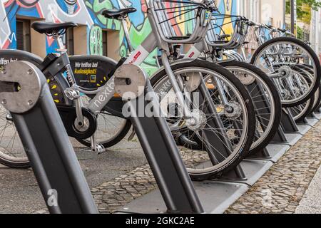 Verschiedene Nextbike-Leihräder an der Ladestation, die von der Supermarktkette Edeka betrieben wird. Stockfoto