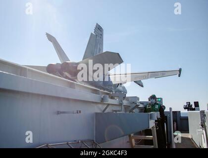 Der Mate (Equipment) der 3. Klasse Jose Machado aus Yorbalinda, Kalifornien, der Luftabteilung der USS Gerald R. Ford (CVN 78) zugewiesen wurde, steht als F/A-18E Super Hornet, das an die „Flying Eagles“ des Strike Fighter Squadron (VFA) 122 angeschlossen ist, als Bogenschutz und startet am 9. März 2021 von Ford aus. Ford führt derzeit im Atlantischen Ozean Beförderungen durch. Stockfoto