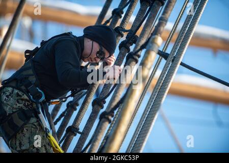 ATLANTISCHER OZEAN (9. März 2021) die US Navy Airman Jennifer Martinez besteigt die Schutzhüllen an Bord der USCGS Eagle (WJX 327), während sie im Atlantischen Ozean unterwegs ist. Matrosen, die der USS Constitution zugewiesen wurden, sind mit Eagle unterwegs, um in der Segelkunst geschult zu werden und die Beziehungen zwischen Marine und Küstenwache weiter auszubauen. Stockfoto