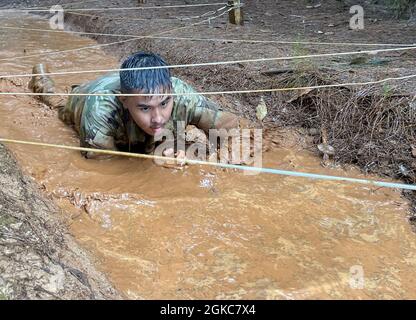 Hawaii Army National Guard Pfc. Kaeo J. New kriecht durch schlammiges Wasser während des Hawaii Best Warrior Competition (BWC) Hindernisparcours 2021 in Area X, Schofield Barracks, Hawaii, 6. März 2021. Der BWC ist ein jährliches dreitägiges Event, bei dem Soldaten und nicht-beauftragte Offiziere der Hawaii Army National Guard und der Hawaii Army Reserve gegeneinander antreten, um den Titel „Bester Krieger“ zu erhalten. Der BWC testet die individuelle Fähigkeit der Soldaten, herausfordernde Szenarien und kampforientierte Ereignisse anzupassen und zu überwinden, und testet ihre technischen und taktischen Fähigkeiten unter Stress und extremer Ermüdung. Stockfoto