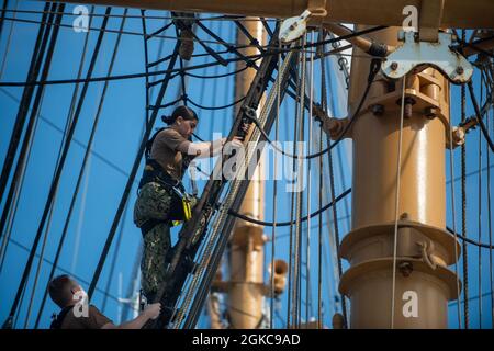 ATLANTISCHER OZEAN (10. März 2021) der US-Navy-Airman Megan Kearns besteigt die Schutzhüllen an Bord des USCGS Eagle (WJX 327), während er im Atlantik unterwegs ist. Matrosen, die der USS Constitution zugewiesen wurden, sind mit Eagle unterwegs, um in der Segelkunst geschult zu werden und die Beziehungen zwischen Marine und Küstenwache weiter auszubauen. Stockfoto