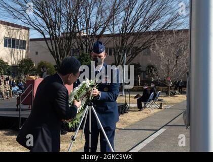 Col. Andrew Campbell, 374. Kommandant des Luftlift-Flügels, Und Takahisa Matsuda, die Generaldirektorin des North Kanto Defense Bureau, platziert einen Kranz an der Basis eines japanischen Fahnenmastes während einer Zeremonie zum 10. Jahrestag des großen Erdbebens in Ostjapan und der Operation Tomodachi Support-Bemühungen auf der Yokota Air Base, Japan, 11. März 2021. Der Kranz stellt den Verlust von fast 16,000 Menschenleben während des Erdbebens und des darauf folgenden Tsunamis dar. Stockfoto