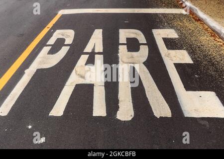 Asphaltweg frisch mit etwas Schmutz gemacht und in der oberen rechten Ecke der Pollen eines Baumes. Das Wort STOP ist auf dem Foto (auf Portugiesisch) Stockfoto