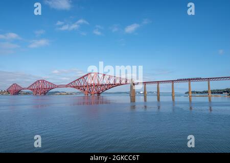 South Queensferry, Edinburgh, Schottland 7. September 2021 - Ein Zug, der an einem strahlend sonnigen Tag mit blauem Himmel über die Forth Bridge fährt Stockfoto