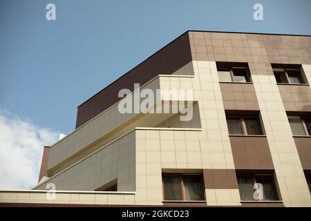 Modernes Gebäude. Beige und braune Verkleidung am Bürogebäude. Architektonische Details. Drei Etagen im Rahmen. Stockfoto