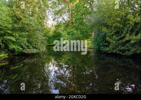 The Knoll, ein kleiner Park in Hayes, Kent, Großbritannien. Reflexionen auf dem Wasser eines kleinen Sees mit Bäumen. Hayes liegt im Stadtteil Bromley im Großraum London. Stockfoto