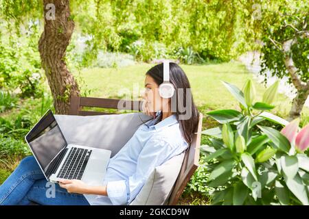 Attraktive junge Frau im Garten, während Video-Chat in den sozialen Medien im grünen Garten Stockfoto