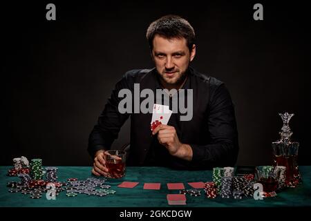 Bärtiger Casino Spieler Mann, der Poker auf dem grünen Tisch spielt Stockfoto