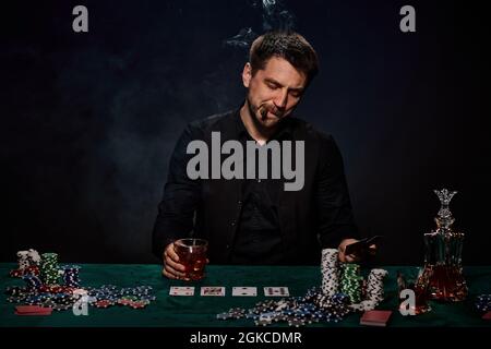 Bärtiger Casino Spieler Mann, der Poker auf dem grünen Tisch spielt Stockfoto
