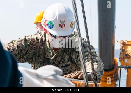 Sagami Wan (11. März 2021) - Gunners Mate 1. Klasse Jonathan ward aus Forsyth, Georgia, ein Seemann, der dem Naval Munitions Command, der Ostasien Division, Unit Yokosuka, zugewiesen wurde, transportiert Munitionskisten während einer Ladung an Bord des US-Flaggschiffs der 7. Flotte USS Blue Ridge (LCC 19). Blue Ridge ist das älteste operationelle Schiff der Marine und arbeitet als Kommandoschiff der 7. Flotte aktiv an der Förderung von Beziehungen zu Verbündeten und Partnern in der Indo-Pazifik-Region. Stockfoto