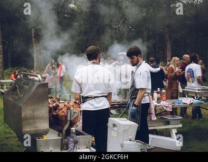 Köche kochen bei einer Veranstaltung im Freien einen Schweinebraten Stockfoto