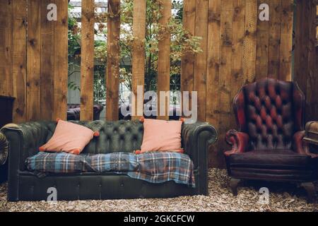 Ein rustikal aussehendes antikes Sofa vor einer verwitterten Holzwand Stockfoto